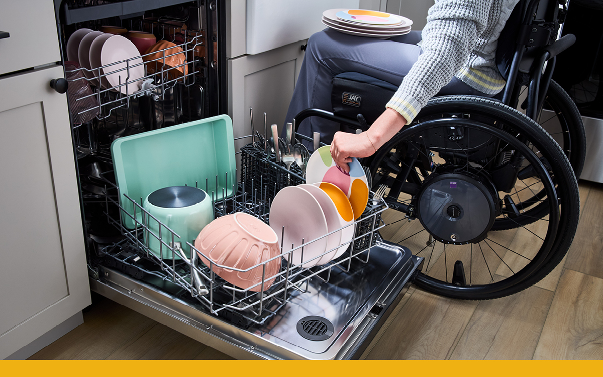 person in a wheelchair can be seen using the spin and load dishwasher lower rack with ease while loading dishes
