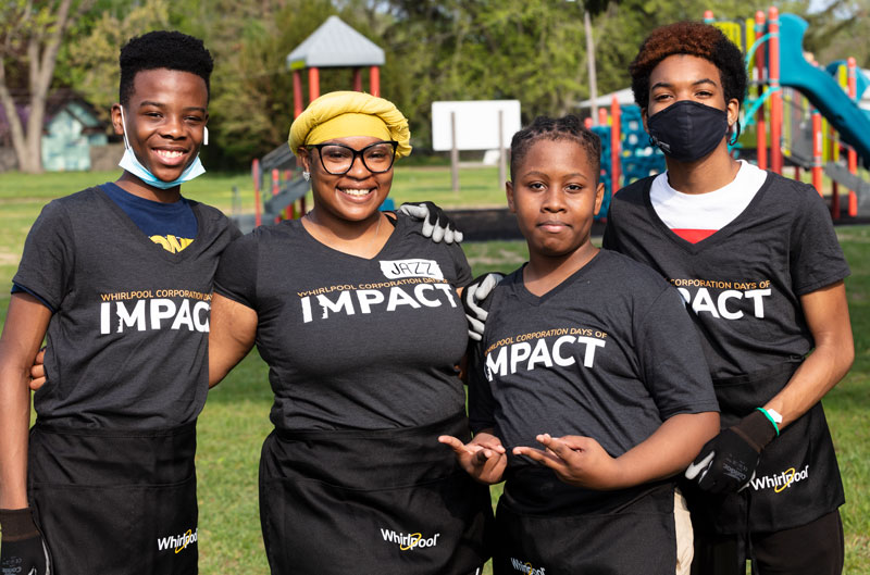 Three students from Benton Harbor pose with a Whirlpool employee as they volunteer at a Union Park clean-up day