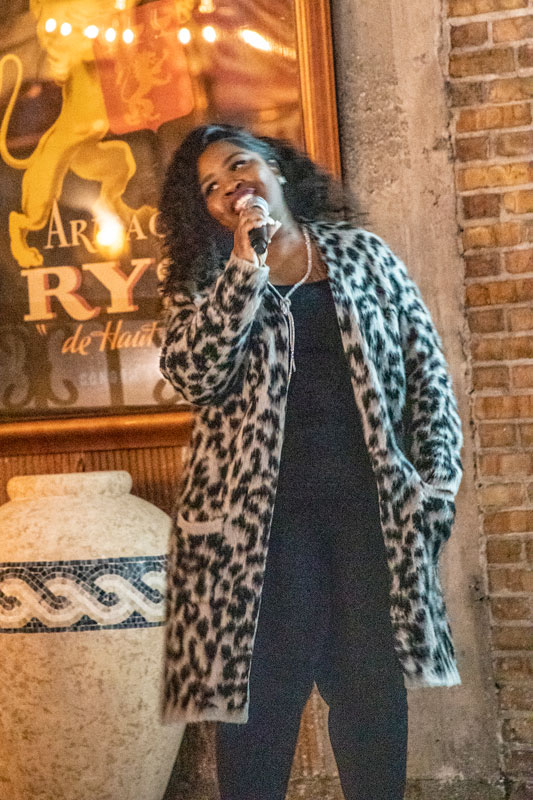 Smiling woman wearing a leopard patterned long jacket holding a microphone