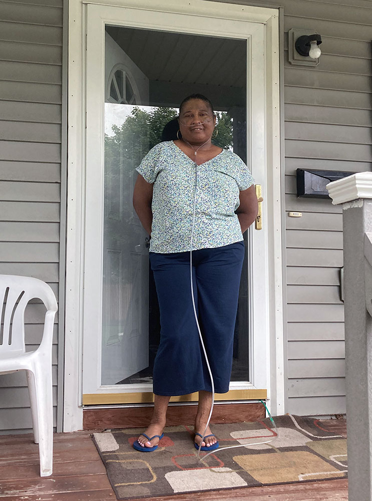 Mattie, a Habitat for Humanity homeowner, stands smiling in the doorframe of her home